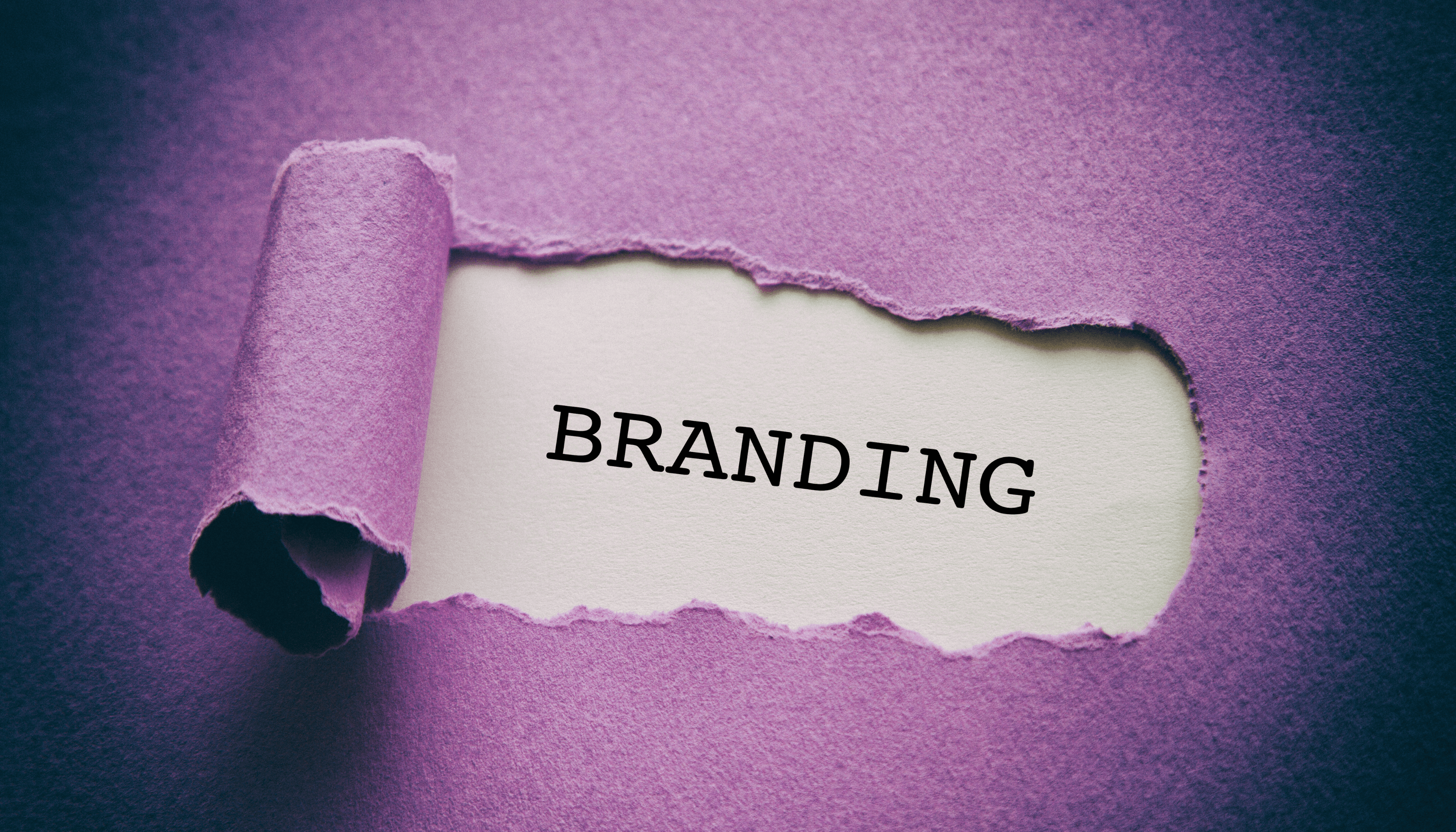 The word 'Branding' revealed through torn purple paper, symbolizing the importance of brand identity. Keywords: AI for daily life, branding, brand identity